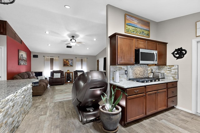 9616 Eucariz Ave SW, Albuquerque, NM 87121 - kitchen with stainless steel appliances, light wood finished floors, ceiling fan, open floor plan, and decorative backsplash