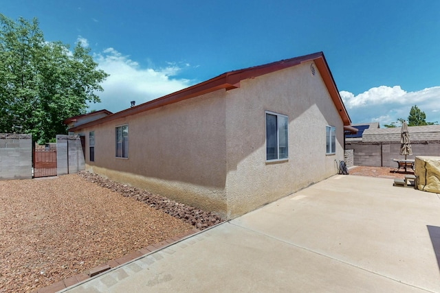 9616 Eucariz Ave SW, Albuquerque, NM 87121 - view of side of property with a gate, stucco siding, and a patio