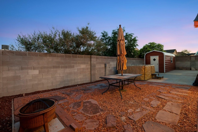9616 Eucariz Ave SW, Albuquerque, NM 87121 - patio terrace at dusk featuring a storage shed, a patio, a fenced backyard, and outdoor dining space
