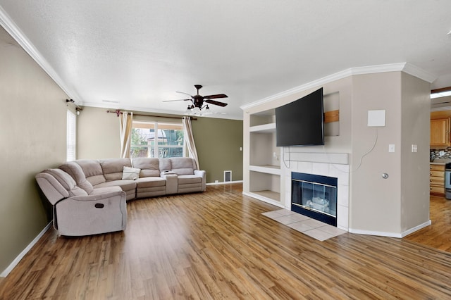 701 Autumn Meadows Dr, Rio Rancho, NM 87144 - living area with crown molding, light wood-style floors, a tile fireplace, and ceiling fan