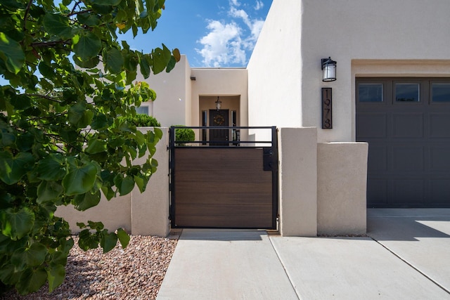 1978 Castle Peak Loop NE, Rio Rancho, NM 87144 - view of front facade with a gate, stucco siding, and concrete driveway