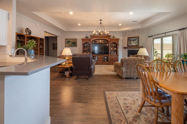 1978 Castle Peak Loop NE, Rio Rancho, NM 87144 - dining area with a raised ceiling, dark wood finished floors, recessed lighting, a brick fireplace, and a chandelier