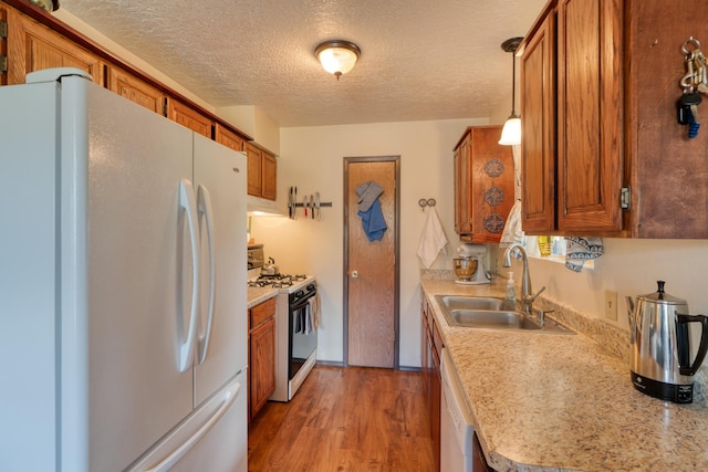 1 Dinosaur Rd, Stanley, NM 87056 - kitchen with white appliances, brown cabinetry, light countertops, a textured ceiling, and light wood-type flooring