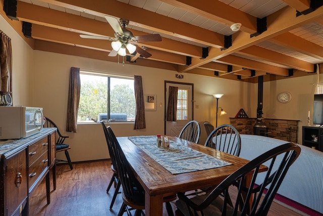 1 Dinosaur Rd, Stanley, NM 87056 - dining room with beamed ceiling, a ceiling fan, wood finished floors, and a wood stove