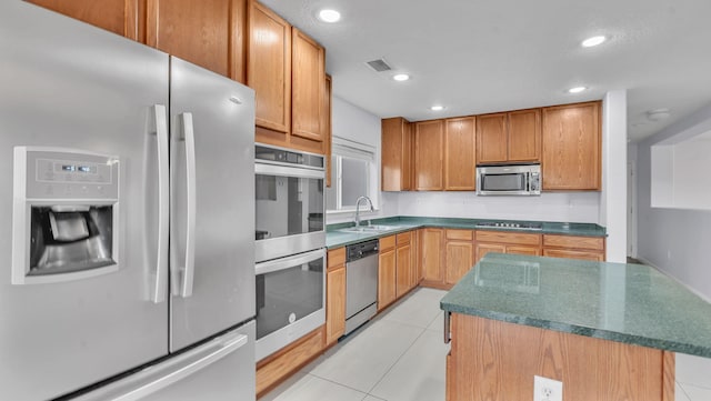3536 Clear Creek Pl, Rio Rancho, NM 87144 - kitchen with stainless steel appliances, light tile patterned flooring, a kitchen island, dark countertops, and recessed lighting