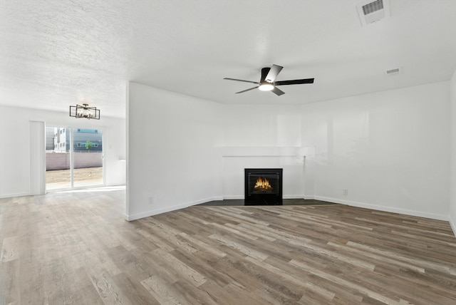 9638 Morrow Ave NE, Albuquerque, NM 87112 - unfurnished living room with wood finished floors, a chandelier, a lit fireplace, and a ceiling fan