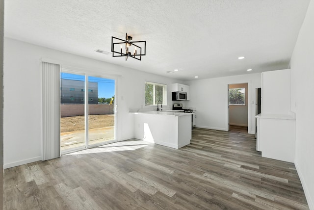 9638 Morrow Ave NE, Albuquerque, NM 87112 - kitchen with stainless steel appliances, white cabinets, wood finished floors, light countertops, and a chandelier