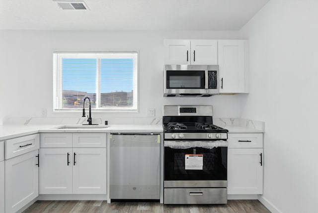 9638 Morrow Ave NE, Albuquerque, NM 87112 - kitchen with stainless steel appliances, light wood-style floors, white cabinetry, and light stone countertops