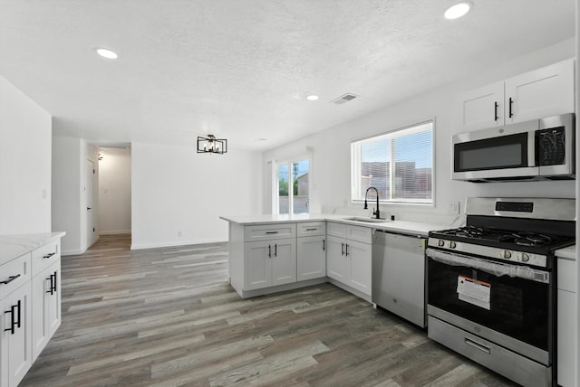9638 Morrow Ave NE, Albuquerque, NM 87112 - kitchen with stainless steel appliances, recessed lighting, light countertops, light wood finished floors, and white cabinetry