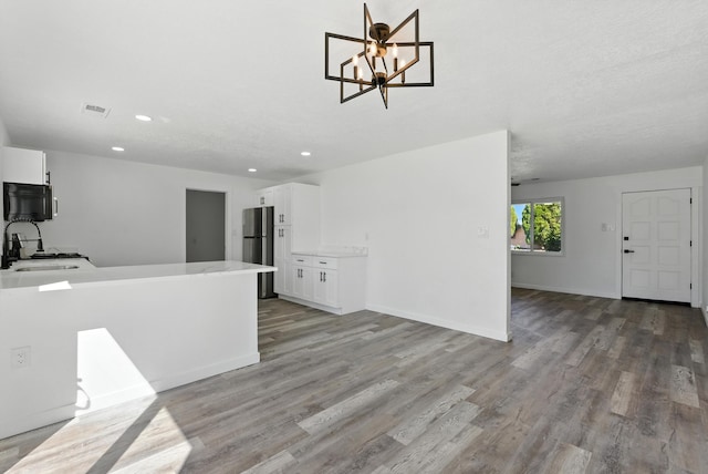9638 Morrow Ave NE, Albuquerque, NM 87112 - kitchen with white cabinets, light wood finished floors, freestanding refrigerator, recessed lighting, and a chandelier