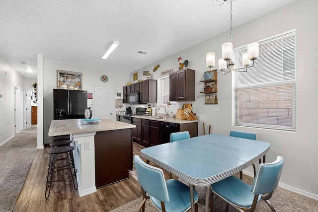 6383 Gannett Dr NE, Rio Rancho, NM 87144 - kitchen with black appliances, dark brown cabinetry, a breakfast bar area, a chandelier, and a kitchen island
