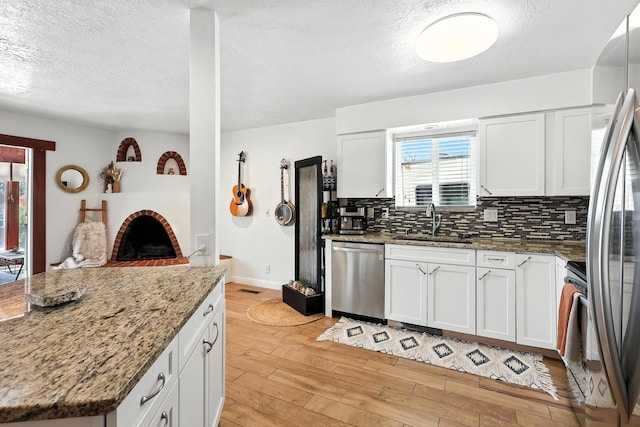 120 Itasca Rd SE, Rio Rancho, NM 87124 - kitchen with appliances with stainless steel finishes, a textured ceiling, light wood-type flooring, backsplash, and white cabinetry