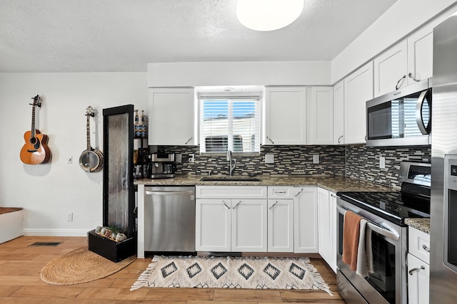 120 Itasca Rd SE, Rio Rancho, NM 87124 - kitchen with appliances with stainless steel finishes, light wood finished floors, backsplash, white cabinets, and stone counters