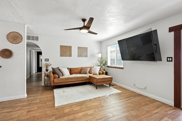 120 Itasca Rd SE, Rio Rancho, NM 87124 - living area with arched walkways, ceiling fan, light wood-style flooring, and a textured ceiling