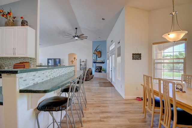 2 Partridge Ct, Peralta, NM 87042 - kitchen featuring a breakfast bar area, light wood-style flooring, dark countertops, ceiling fan, and white cabinetry