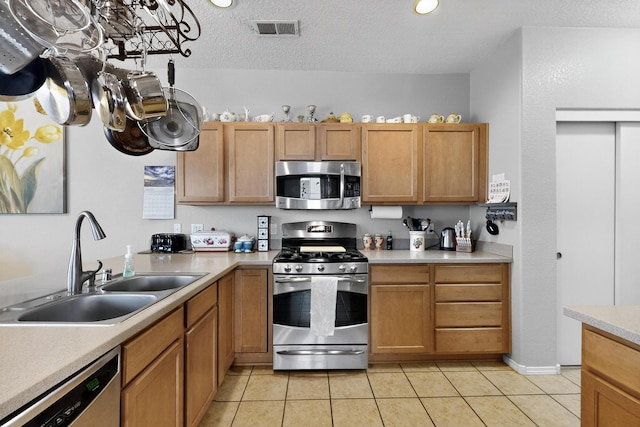 1969 Cortina Loop SE, Albuquerque, NM 87124 - kitchen with stainless steel appliances, light countertops, light tile patterned floors, a textured ceiling, and brown cabinetry