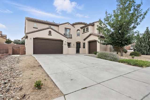 43 Vista Larga Pl NE, Rio Rancho, NM 87124 - mediterranean / spanish home with a gate, driveway, stucco siding, a tile roof, and a balcony