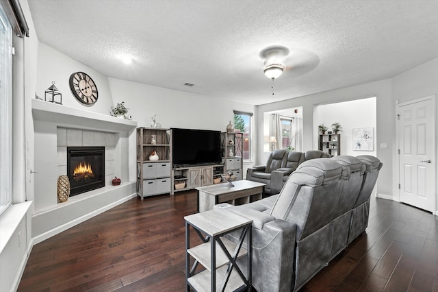 43 Vista Larga Pl NE, Rio Rancho, NM 87124 - living room with a tiled fireplace, dark wood-style floors, a textured ceiling, and a ceiling fan