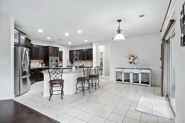 43 Vista Larga Pl NE, Rio Rancho, NM 87124 - kitchen featuring appliances with stainless steel finishes, decorative backsplash, a kitchen bar, recessed lighting, and an island with sink