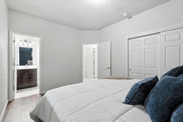 43 Vista Larga Pl NE, Rio Rancho, NM 87124 - bedroom featuring light wood-style flooring, a closet, a textured ceiling, and ensuite bathroom