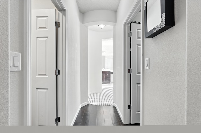 43 Vista Larga Pl NE, Rio Rancho, NM 87124 - hallway with arched walkways, dark wood-style floors, and a textured wall