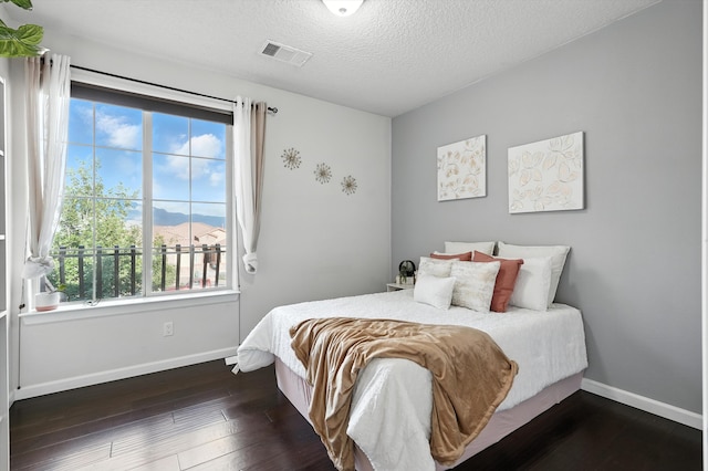 43 Vista Larga Pl NE, Rio Rancho, NM 87124 - bedroom featuring multiple windows, hardwood / wood-style floors, a mountain view, and a textured ceiling