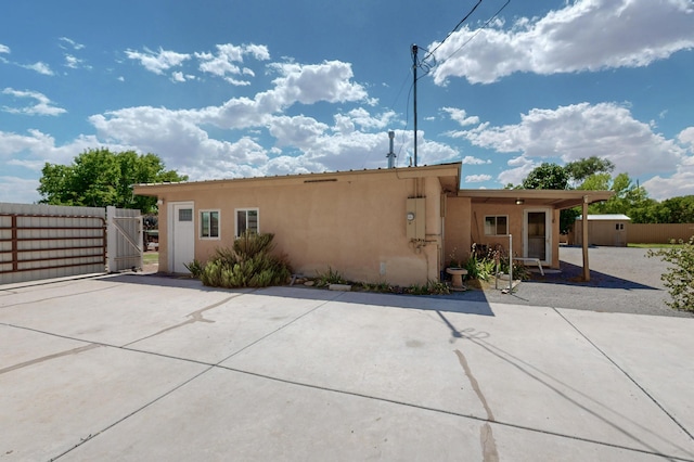 855 Foxcroft Loop, Bosque Farms, NM 87068 - rear view of house featuring stucco siding, a gate, a storage unit, and a patio