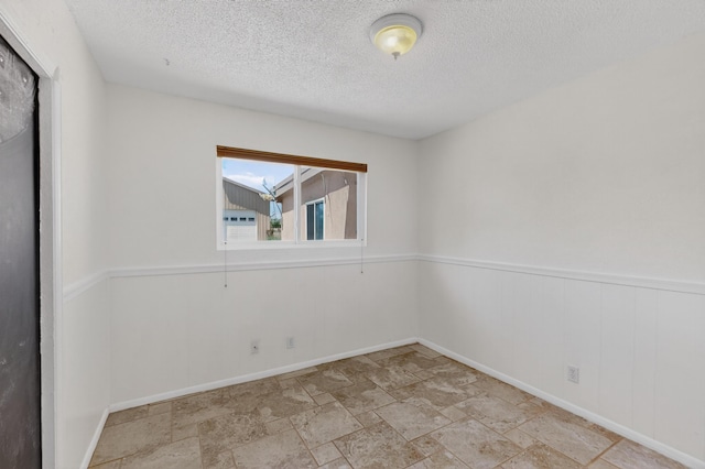 855 Foxcroft Loop, Bosque Farms, NM 87068 - unfurnished room with a textured ceiling, stone finish flooring, and a wainscoted wall