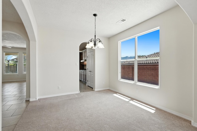 6903 Wrangell Loop NE, Rio Rancho, NM 87144 - unfurnished dining area with arched walkways, a chandelier, a textured ceiling, and light carpet