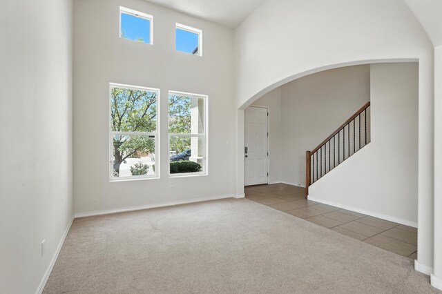 6903 Wrangell Loop NE, Rio Rancho, NM 87144 - carpeted foyer featuring arched walkways, a high ceiling, tile patterned flooring, and stairway