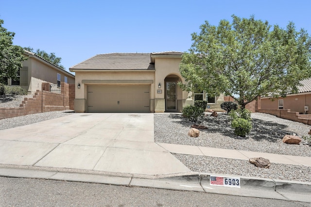 6903 Wrangell Loop NE, Rio Rancho, NM 87144 - view of front of home featuring driveway, stucco siding, an attached garage, and a tiled roof