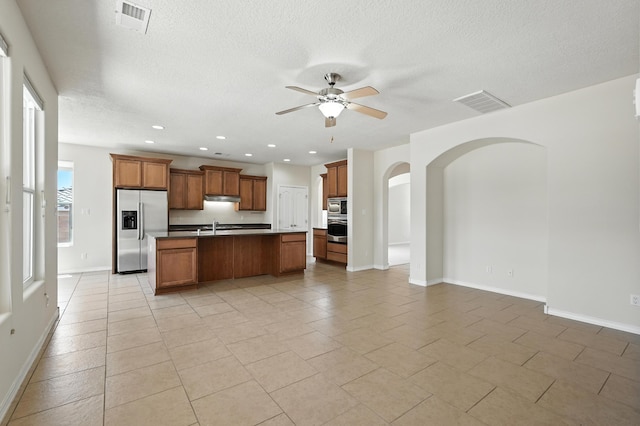6903 Wrangell Loop NE, Rio Rancho, NM 87144 - kitchen featuring appliances with stainless steel finishes, open floor plan, a ceiling fan, a kitchen island with sink, and under cabinet range hood