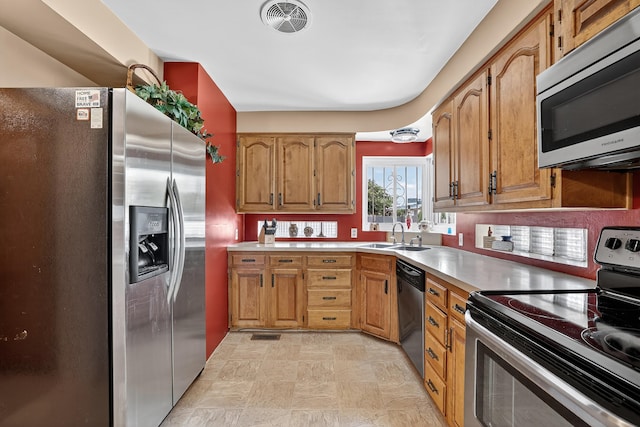 302 Crestview Dr SW, Albuquerque, NM 87105 - kitchen with stainless steel appliances, light countertops, brown cabinetry, and stone finish flooring