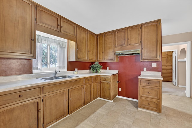 302 Crestview Dr SW, Albuquerque, NM 87105 - kitchen with under cabinet range hood, brown cabinets, light countertops, and arched walkways