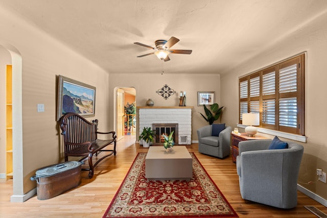 704 Tyler Rd NW, Los Ranchos, NM 87107 - living area with arched walkways, a ceiling fan, wood finished floors, and a brick fireplace