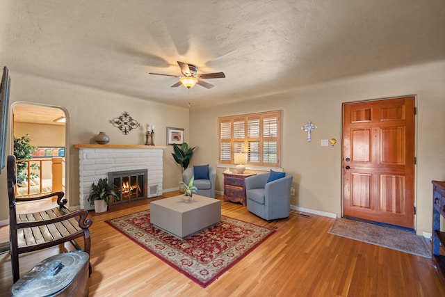 704 Tyler Rd NW, Los Ranchos, NM 87107 - living area with a ceiling fan, wood finished floors, a brick fireplace, and arched walkways