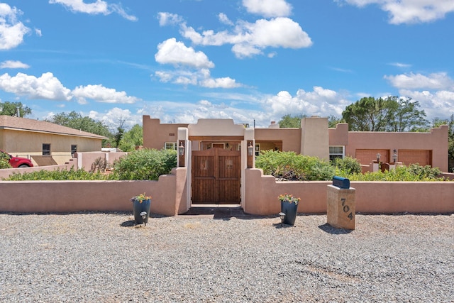 704 Tyler Rd NW, Los Ranchos, NM 87107 - pueblo revival-style home featuring a fenced front yard, stucco siding, and a gate