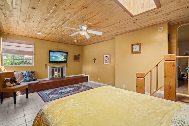 704 Tyler Rd NW, Los Ranchos, NM 87107 - bedroom with wooden ceiling, tile patterned flooring, a warm lit fireplace, and a ceiling fan