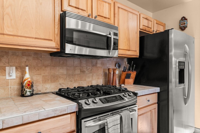 704 Tyler Rd NW, Los Ranchos, NM 87107 - kitchen with stainless steel appliances, tile counters, light brown cabinetry, and tasteful backsplash