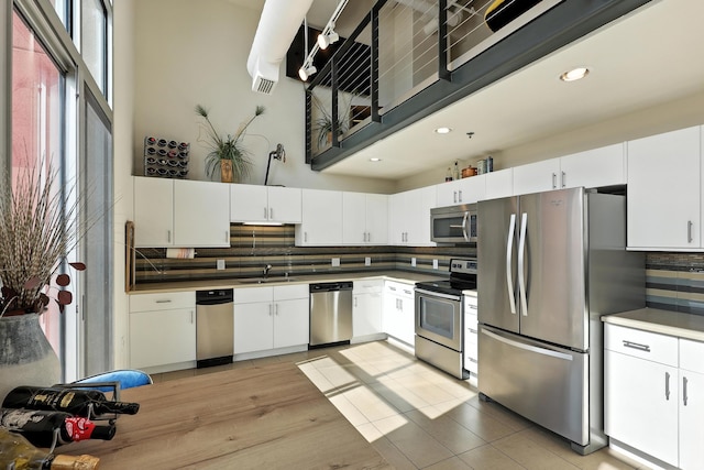 524 Central Ave SW # 803, Albuquerque, NM 87102 - kitchen with stainless steel appliances, tasteful backsplash, white cabinetry, a towering ceiling, and dark countertops