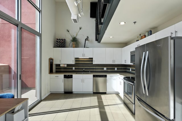 524 Central Ave SW # 803, Albuquerque, NM 87102 - kitchen with stainless steel appliances, light tile patterned floors, decorative backsplash, dark countertops, and white cabinetry