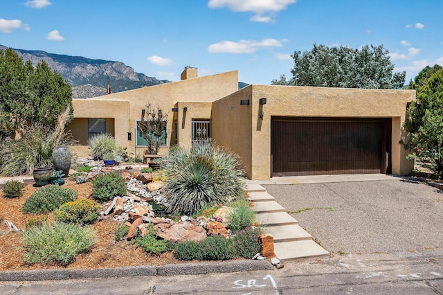 1865 Tramway Terrace Loop NE, Albuquerque, NM 87122 - pueblo revival-style home featuring a garage, stucco siding, a mountain view, asphalt driveway, and a chimney