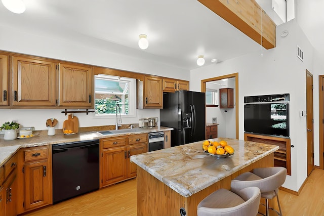1865 Tramway Terrace Loop NE, Albuquerque, NM 87122 - kitchen with black appliances, light wood-style floors, a breakfast bar, and a center island