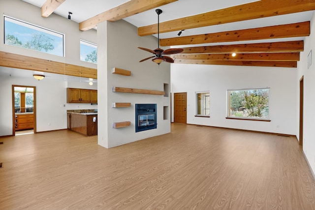 1865 Tramway Terrace Loop NE, Albuquerque, NM 87122 - unfurnished living room featuring light wood finished floors, a glass covered fireplace, high vaulted ceiling, a ceiling fan, and beamed ceiling