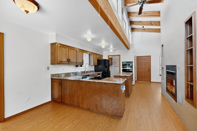 1865 Tramway Terrace Loop NE, Albuquerque, NM 87122 - kitchen with black appliances, brown cabinetry, light wood-type flooring, a peninsula, and beam ceiling