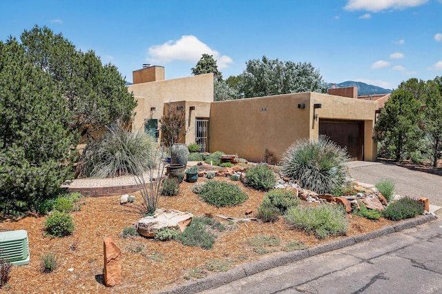 1865 Tramway Terrace Loop NE, Albuquerque, NM 87122 - pueblo-style house with stucco siding, an attached garage, a chimney, and asphalt driveway