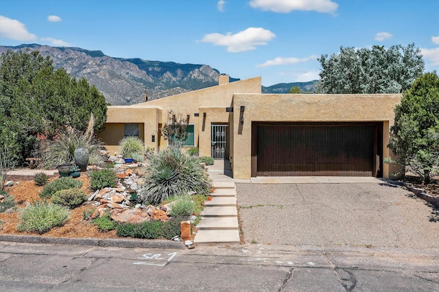 1865 Tramway Terrace Loop NE, Albuquerque, NM 87122 - pueblo-style home featuring a garage, stucco siding, a mountain view, asphalt driveway, and a chimney