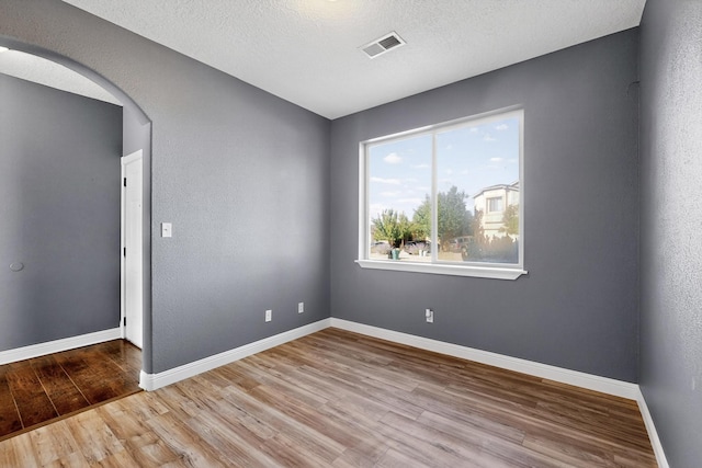 1324 Desert Paintbrush Loop, Rio Rancho, NM 87144 - spare room with arched walkways, wood finished floors, and a textured ceiling