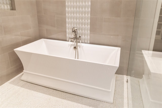 bathroom with tile walls and a tub