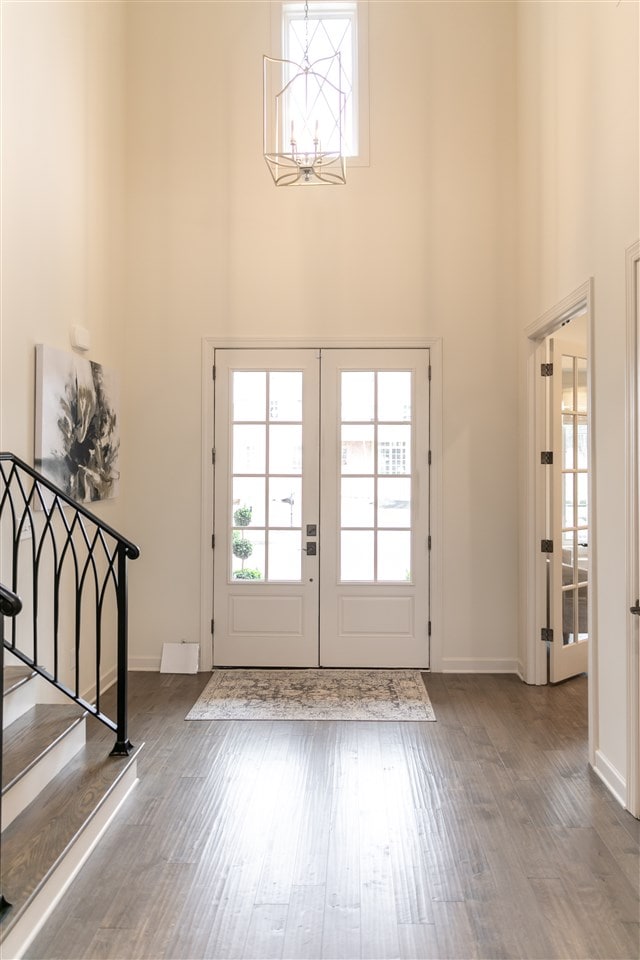 entryway with hardwood / wood-style flooring, a high ceiling, an inviting chandelier, and french doors